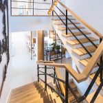 Bright modern wooden staircase with black metal railing